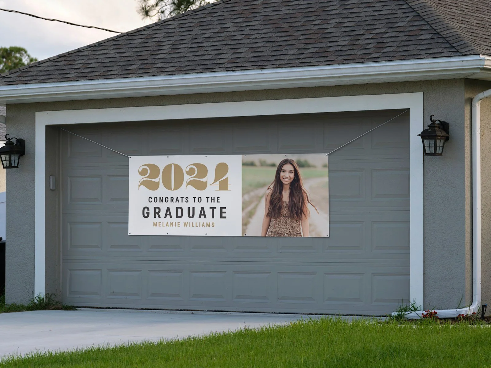 Garage door with a banner celebrating a graduate named Melanie Williams, with a picture of her smiling outdoors.