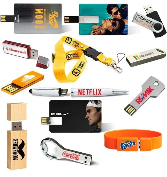 Collection of various USB flash drives and promotional items. Items include a Nike SB USB, a photo card USB, a Honeywell USB, a yellow Pages USB lanyard, a Microsoft USB, a Netflix pen, a Remax USB, a Nike Just Do It USB, a Coca-Cola keychain USB, a Fanta wristband, a Mover USB, and a USB with a photo of a man wearing a headband.