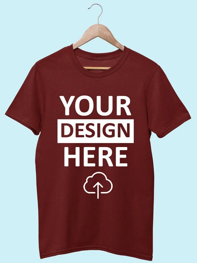 Red T-shirt hanging on a wooden hanger against a light blue background, with the text 'YOUR DESIGN HERE' and a cloud upload icon printed on it.